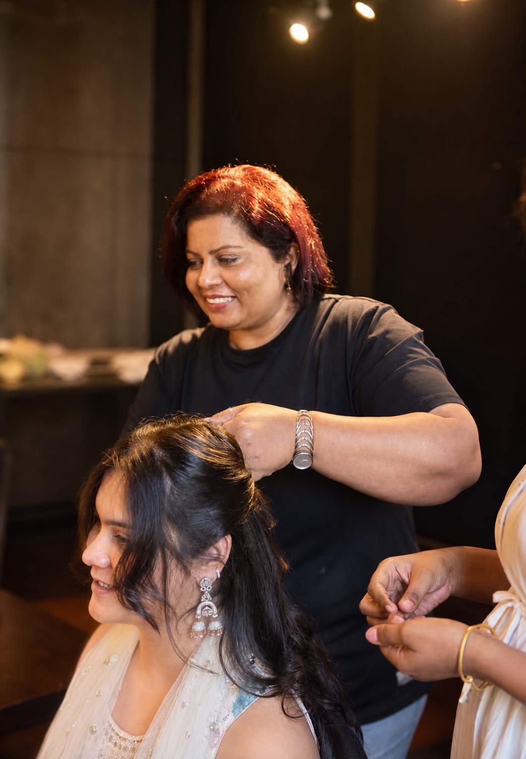 A Salon Nayana stylist finishing a wedding guest's hair while an assistant helps nearby