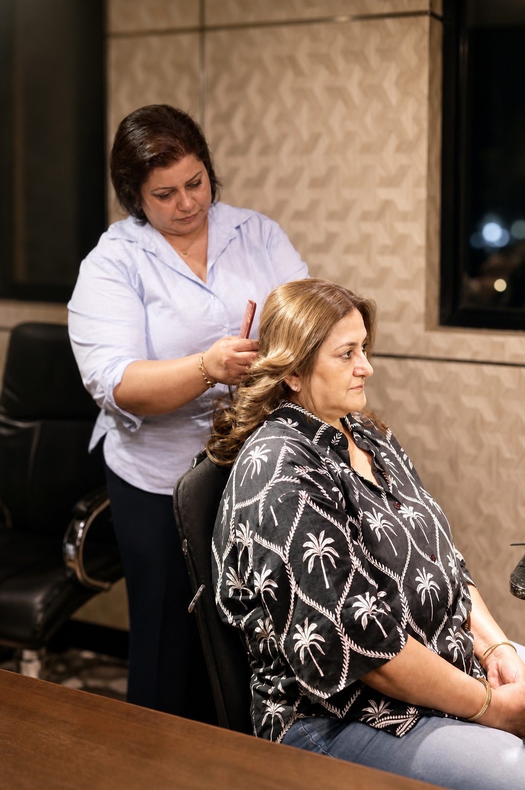 A wedding guest having softly curled hair finished by a Salon Nayana stylist
