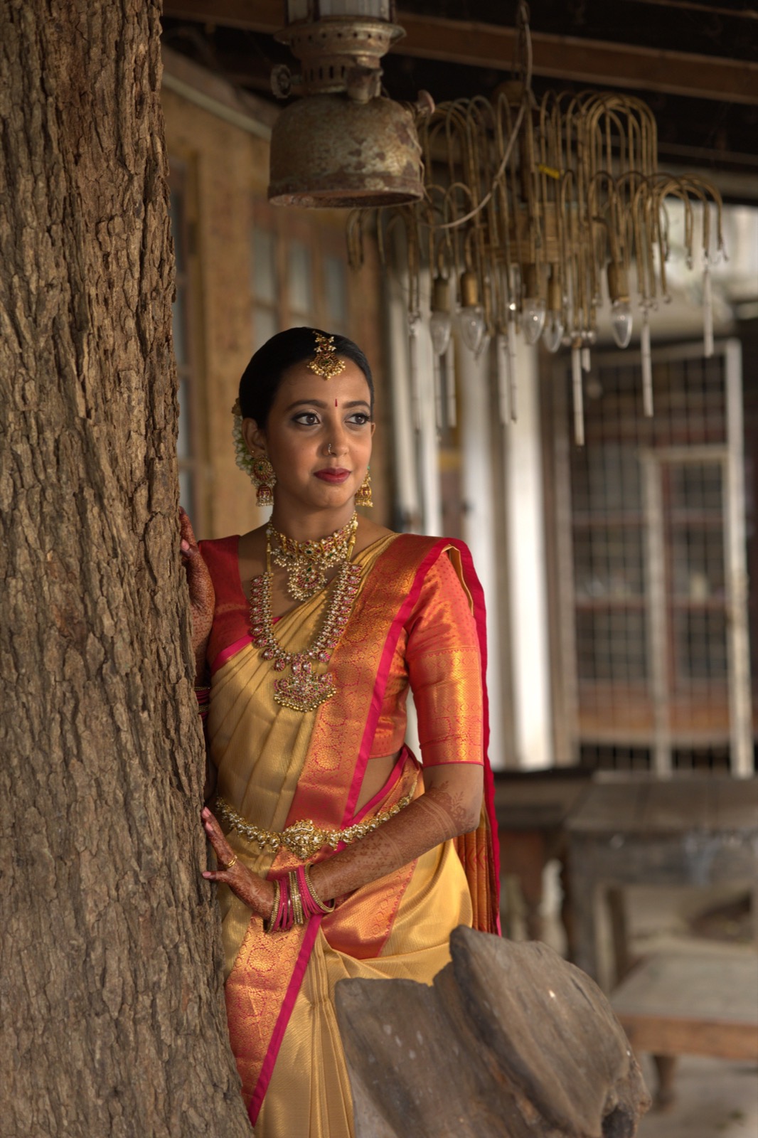 Bride in a gold and coral sari with traditional jewellery and Salon Nayana bridal styling